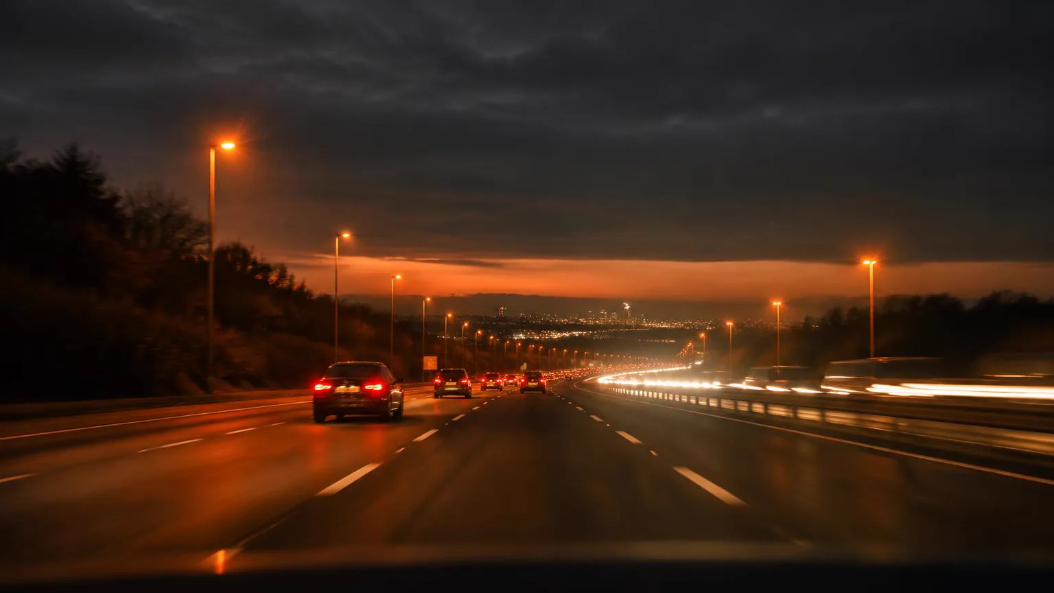 English motorway at dusk with light trails stretching towards a distant city skyline